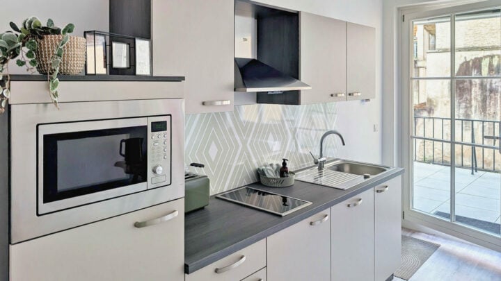 MainZauber Apartments früher MainTerrasse Miltenberg am Main - Luxuriöse Ferienwohnung: Moderne Küche mit weißen Möbeln, vollausgestattet, viel Tageslicht, perfekte Unterkunft in Miltenberg.