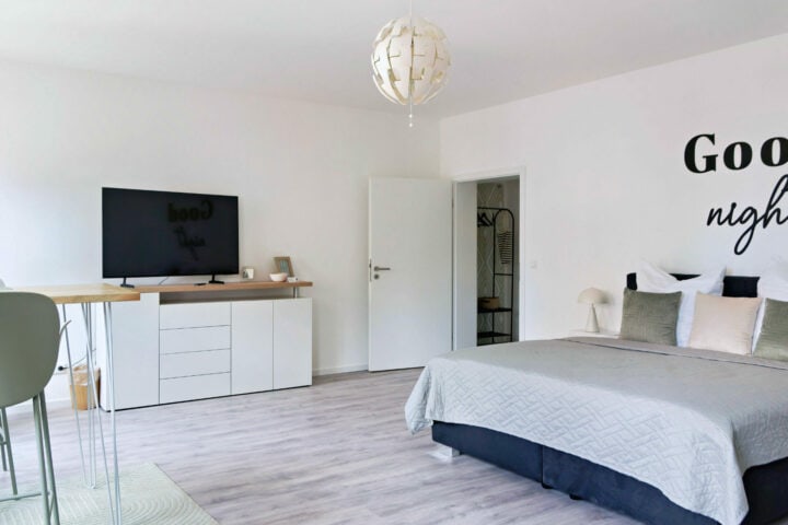 MainZauber Apartments früher MainTerrasse Miltenberg am Main - Modernes, minimalistisches Schlafzimmer in der luxuriösen Ferienwohnung in der Altstadt mit großem Bett, TV und stilvollem Design.