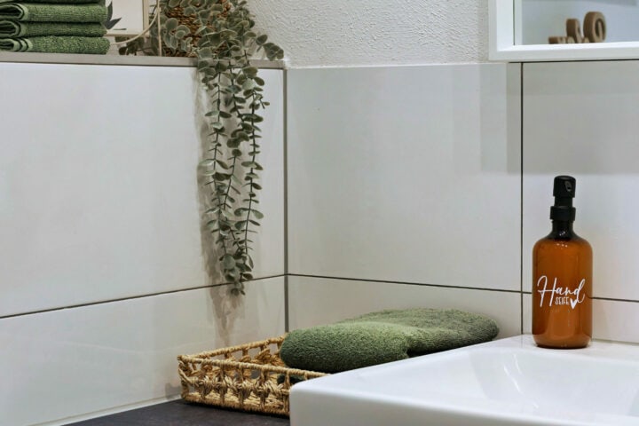 MainZauber Apartments früher MainTerrasse Miltenberg am Main - Luxus-Badezimmer in der Ferienwohnung AltstadtZauber: Korb mit grünen Handtüchern, Lotion, Pflanzen - Ihre Top-Unterkunft.