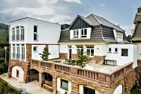 MainZauber Apartments Miltenberg am Main - Entdecken Sie die perfekte Ferienwohnung für Ihren Kurzurlaub, die eine luxuriöse Mischung aus moderner und traditioneller Architektur bietet. Diese exquisite Luxuswohnung für den Urlaub verfügt über große Fenster, die natürliches Licht hereinlassen, ein wunderschön gefliestes Dach und eine geräumige Terrasse, die sich perfekt zum Sitzen im Freien eignet. Erleben Sie wahre Eleganz auf der unteren Ebene mit atemberaubenden Steinbögen, alles vor der ruhigen Kulisse üppigen Grüns. Ihre Traumunterkunft erwartet Sie!
