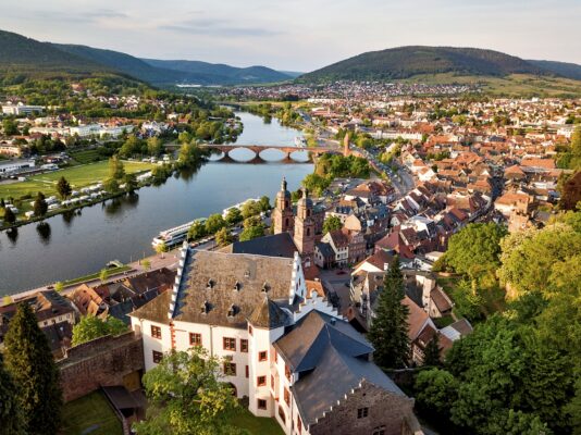 MainZauber Apartments früher MainTerrasse Miltenberg am Main - Entdecken Sie Ihre perfekte Ferienwohnung in einer atemberaubenden europäischen Stadt, in der Geschichte auf Natur trifft. Stellen Sie sich vor, Sie entspannen in einer luxuriösen Unterkunft mit atemberaubendem Blick auf einen sich schlängelnden Fluss und das ikonische historische Schloss und die Kirche, eingebettet in üppiges Grün und traditionelle Architektur. Genießen Sie die nahtlose Verbindung mit einer charmanten Steinbrücke, die beide Flussufer verbindet, während sanfte Hügel eine ruhige Kulisse für Ihren Kurzurlaub bieten. Egal, ob Sie nach Luxusapartments für den Urlaub oder einfach nach einem malerischen Ausflug suchen, dieser bezaubernde Ort verspricht ein unvergessliches Erlebnis.