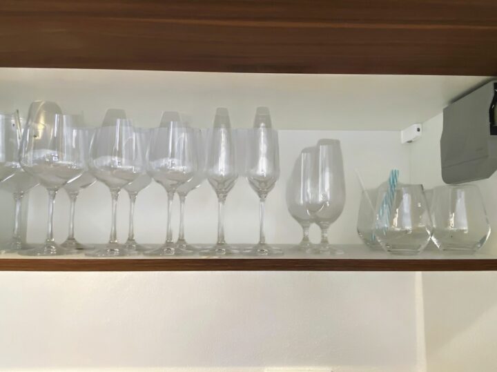MainZauber Apartments früher MainTerrasse Miltenberg am Main - Erleben Sie den perfekten Urlaub in unserem Luxusapartment, das für Ihren ultimativen Komfort und Ihre Entspannung konzipiert wurde. Unser elegant eingerichteter Raum verfügt über ein anspruchsvolles Holzregal mit einer exquisiten Sammlung von Glaswaren, darunter Weingläser, ein stilvoller Kelch und moderne Trinkbecher mit gestreiften Strohhalmen – alles vor einer schicken hellen Wand, die das Ambiente aufwertet. Finden Sie Ihre ideale Unterkunft in diesem atemberaubenden Ferienapartment, in dem jedes Detail darauf ausgelegt ist, Ihr Urlaubserlebnis zu verbessern.