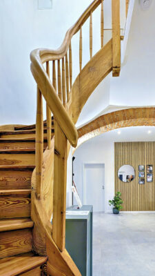 MainZauber Apartments früher MainTerrasse Miltenberg am Main - Erleben Sie die perfekte Mischung aus moderner Eleganz und Komfort in dieser luxuriösen Ferienwohnung. Beim Betreten führt eine beeindruckende Wendeltreppe aus Holz mit einem glatten, hellen Finish anmutig in die oberen Stockwerke. Diese exquisite Unterkunft ist im Sinne einer zeitgenössischen Ästhetik gestaltet und verfügt über helle Beleuchtung, die das elegante Interieur hervorhebt. Bewundern Sie das stilvolle Dekor, das eine schicke Topfpflanze, einen eleganten runden Spiegel und ein auffälliges Lattenholzpaneel an der Wand umfasst. Diese Ferienwohnung bietet den idealen Rückzugsort für alle, die während ihres Aufenthalts sowohl Schönheit als auch Entspannung suchen.