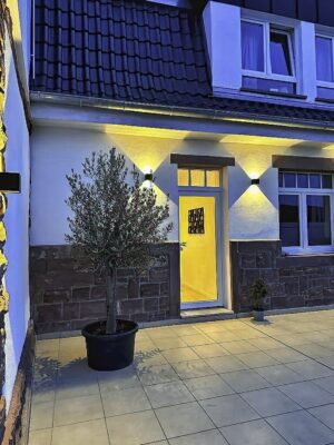 MainZauber Apartments Miltenberg am Main - Entdecken Sie mit dieser charmanten Ferienwohnung den perfekten Rückzugsort für Ihren nächsten Urlaub. Diese luxuriöse Unterkunft verfügt über ein malerisches Ziegeldach, das durch stimmungsvolles gelbes Licht warm beleuchtet wird und eine einladende Atmosphäre schafft. Stellen Sie sich vor, Sie betreten die elegante Terrasse mit einem Topfbaum, der die ruhige Umgebung noch verstärkt. Die atemberaubende Fassade mit ihren glatten weißen Wänden und exquisiten Steinakzenten verleiht dieser Luxus-Ferienwohnung einen verführerischen Charme. Große Fenster und eine Glastür verbinden nahtlos Stil mit Komfort und sorgen für eine einladende Note, wenn Sie Ihren unvergesslichen Aufenthalt beginnen.
